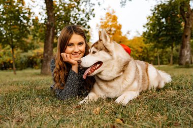 sonbahar parkında genç kadın bir husky köpek ile yürüyor.