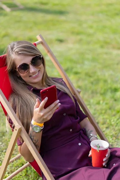 Mädchen Mit Smartphone Und Einem Cocktail Über Die Natur Liegestuhl — Stockfoto