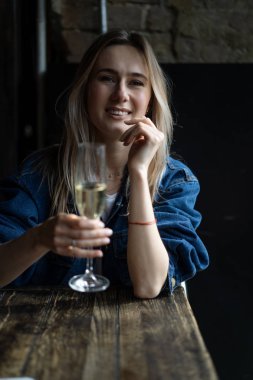 Bir kafede genç, güzel bir kadın, bir kadın şampanya içiyor.
