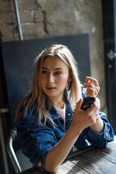 Giovane bella donna in un caffè si guarda allo specchio raddrizza — Foto Stock