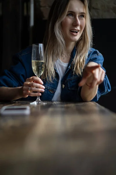 Jovem mulher bonita em um café, uma mulher bebendo champanhe em um — Fotografia de Stock