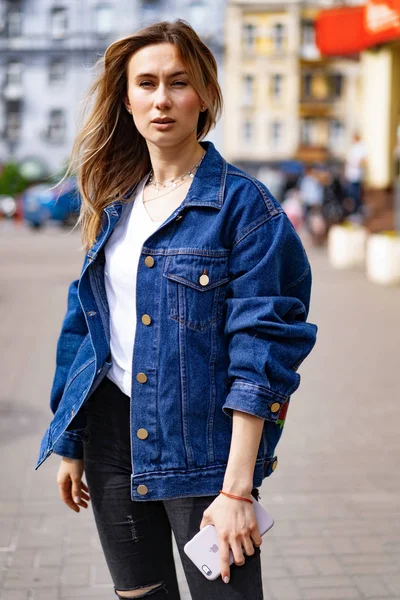 Genç, güzel bir kadın Avrupa 'da şehirde dolaşıyor, sokak fotoğrafı, şehir merkezinde poz veren bir kadın.