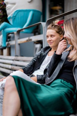 Bir bankta sohbet eden iki genç kadın.