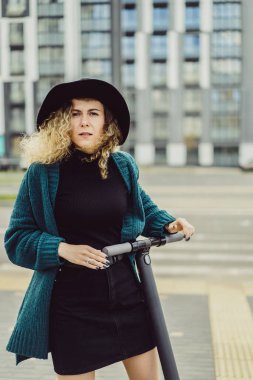 İşe elektrikli scooterla giden genç, güzel bir kadın, modern kız, yeni nesil, elektrik nakli, ekolojik ulaşım, ekolojik ulaşım, gün batımı