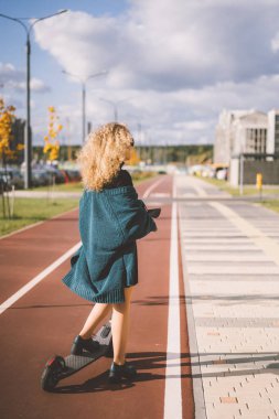 İşe elektrikli scooterla giden genç, güzel bir kadın, modern kız, yeni nesil, elektrik nakli, ekolojik ulaşım, ekolojik ulaşım, gün batımı