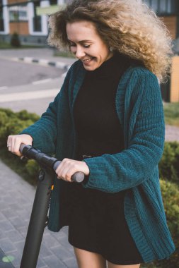 İşe elektrikli scooterla giden genç, güzel bir kadın, modern kız, yeni nesil, elektrik nakli, ekolojik ulaşım, ekolojik ulaşım, gün batımı