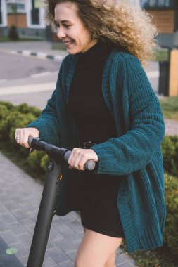 İşe elektrikli scooterla giden genç, güzel bir kadın, modern kız, yeni nesil, elektrik nakli, ekolojik ulaşım, ekolojik ulaşım, gün batımı