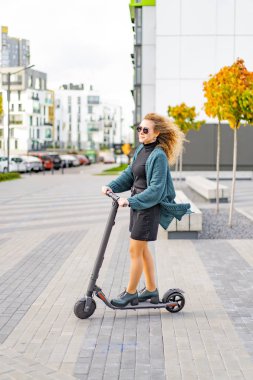 İşe elektrikli scooterla giden genç, güzel bir kadın, modern kız, yeni nesil, elektrik nakli, ekolojik ulaşım, ekolojik ulaşım, gün batımı
