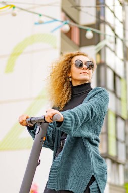 İşe elektrikli scooterla giden genç, güzel bir kadın, modern kız, yeni nesil, elektrik nakli, ekolojik ulaşım, ekolojik ulaşım, gün batımı