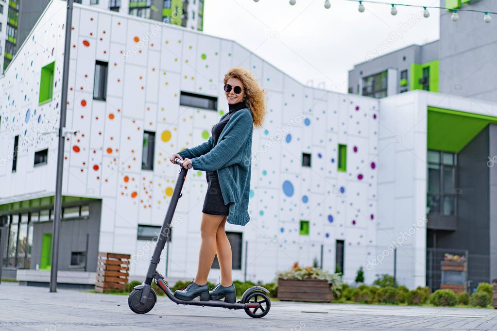 Young beautiful woman riding an electric scooter to work, modern girl, new generation, electric transport, ecology, ecological transport, sunset