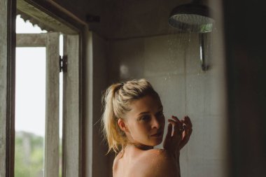 Duş alan mutlu kızın portresi. Güzel gülümseyen beyaz kadın banyodan sonra ıslak saçlarıyla poz veriyor..