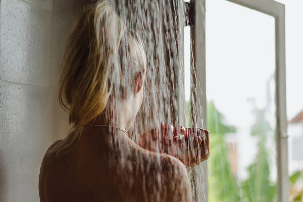 Portrait of happy girl taking shower. Beautiful smiling Caucasian woman posing with wet hair at bathroom after shower.