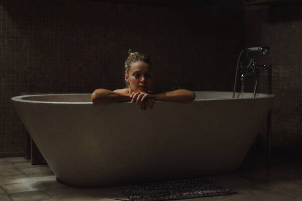 Beautiful smiling Caucasian woman posing with wet hair at bathroom, relaxing in the bath in the bathroom. young woman lying in bathtub.