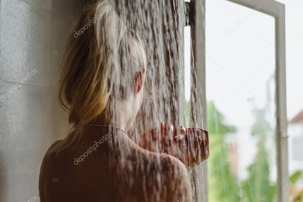 Portrait of happy girl taking shower. Beautiful smiling Caucasian woman posing with wet hair at bathroom after shower.