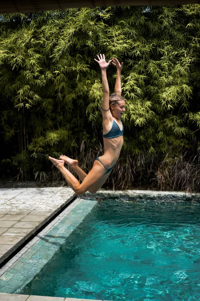 Beautiful young woman is jumping into the pool. fun jump