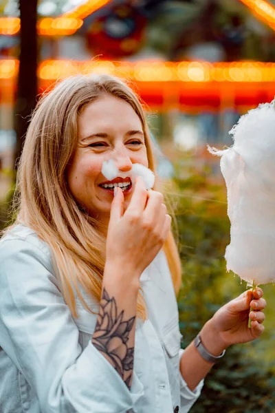 穿着红色衣服和白色斜纹棉布夹克的年轻貌美女人在一个有糖果牙线的游乐园里 — 图库照片