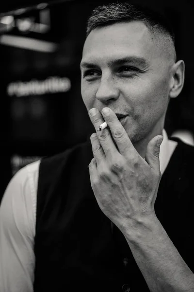 タバコを吸う若い感情的カリスマ男 魅力的な男の煙 感情的な男の肖像画 接近中だ バーテンダーの黒と白の肖像画 — ストック写真