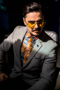 Sarı gözlüklü ve parlak gömlekli genç yakışıklı adam. Yakın plan portre, şovmen.