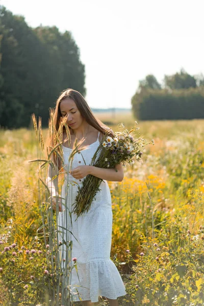 白いドレスに長い髪の若い美しい女性とライ麦と小麦の黄色のフィールドの間で帽子 — ストック写真