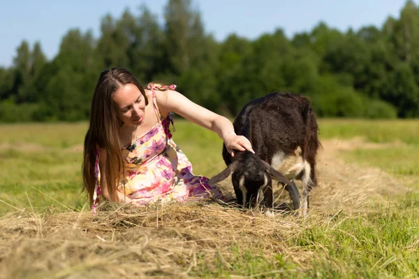 young beautiful woman in the village stroking goats.