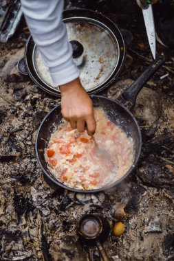 Kamp gezisinde kamp ateşinde yemek pişirdim. Kamp mutfağı, ormanda ateş içinde yemek pişirmek. Kızartma tavası yanıyor. Kamp hayatı konsepti.