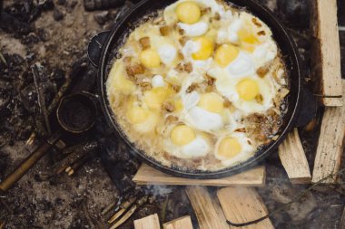 Kamp gezisinde kamp ateşinde yemek pişirdim. Kamp mutfağı, ormanda ateş içinde yemek pişirmek. Kızartma tavası yanıyor. Kamp hayatı konsepti.