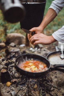 Kamp gezisinde kamp ateşinde yemek pişirdim. Kamp mutfağı, ormanda ateş içinde yemek pişirmek. Kızartma tavası yanıyor. Kamp hayatı konsepti.