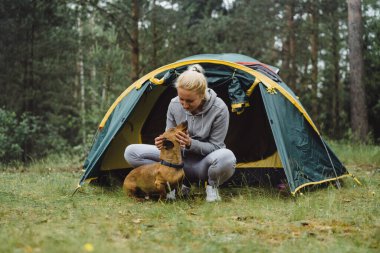 Kamp gezisinde köpeği olan genç bir kadın. Kamp hayatı konsepti.