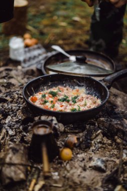 Kamp gezisinde kamp ateşinde yemek pişirdim. Kamp mutfağı, ormanda ateş içinde yemek pişirmek. Kızartma tavası yanıyor. Kamp hayatı konsepti.