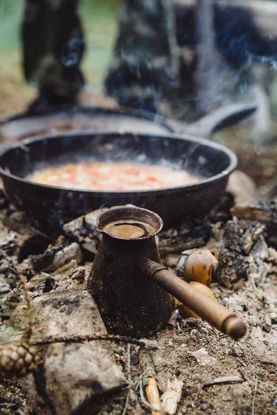 Coffee in Turk made at the stake in a camping trip. Camping kitchen, cooking in the woods on fire. The concept of life in the campaign.