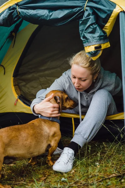 A young woman with a dog on a camping trip. Camping life concept.
