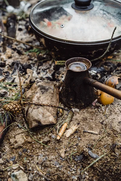 Coffee in Turk made at the stake in a camping trip. Camping kitchen, cooking in the woods on fire. The concept of life in the campaign.