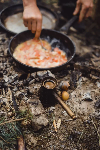 Cooked food on a campfire on a camping trip. Camp kitchen, cooking food in the forest on fire. Frying pan on fire. Camping life concept.