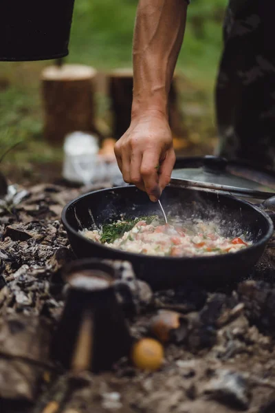 Cooked food on a campfire on a camping trip. Camp kitchen, cooking food in the forest on fire. Frying pan on fire. Camping life concept.