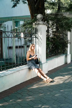 Güneşli bir yaz günü, güzel genç bir kadın sokakta dondurma yiyor..