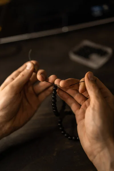 creation of a bracelet from stones, process, hands, close-up.