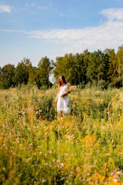 Çavdar ve buğday tarlaları arasında beyaz elbiseli, şapkalı, uzun saçlı genç ve güzel bir kadın. Kırsal tarzda uzun saçlı, çiçekli bir tarlada beyaz bir elbise giyen bir kavram.