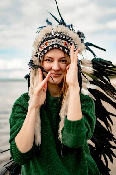 woman wearing an American Indian hat. Close up portrait of shamanic female with Indian feather hat