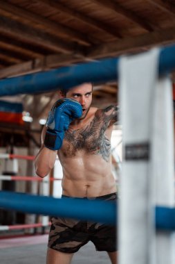 Ringde Muay Thai antrenörüyle antrenman yapmak. Dövmeli beyaz adam ve Asyalı antrenör. Muay thai eğitimi.