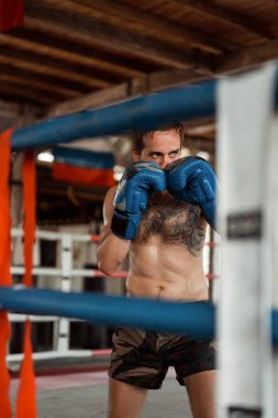 Ringde Muay Thai antrenörüyle antrenman yapmak. Dövmeli beyaz adam ve Asyalı antrenör. Muay thai eğitimi.