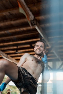 Ringde Muay Thai antrenörüyle antrenman yapmak. Dövmeli beyaz adam ve Asyalı antrenör. Muay thai eğitimi.