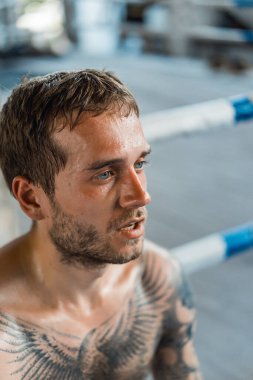 Ringde Muay Thai antrenörüyle antrenman yapmak. Dövmeli beyaz adam ve Asyalı antrenör. Muay thai eğitimi.