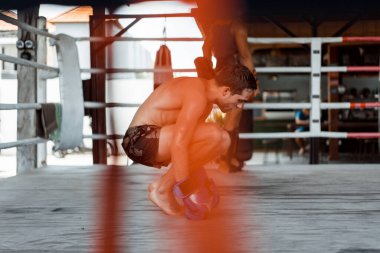 Ringde Muay Thai antrenörüyle antrenman yapmak. Dövmeli beyaz adam ve Asyalı antrenör. Muay thai eğitimi.