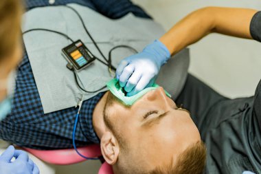 Kofferdam hastası bir diş hekimi tarafından tedavi ediliyor.