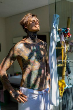 Banyoda duş aldıktan sonra dövmeli yakışıklı bir genç. 