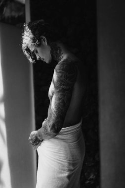 Banyoda duş aldıktan sonra dövmeli yakışıklı bir genç. 