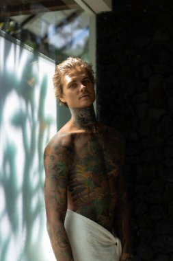 Banyoda duş aldıktan sonra dövmeli yakışıklı bir genç. 