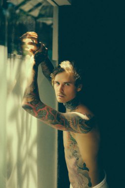 Banyoda duş aldıktan sonra dövmeli yakışıklı bir genç. 