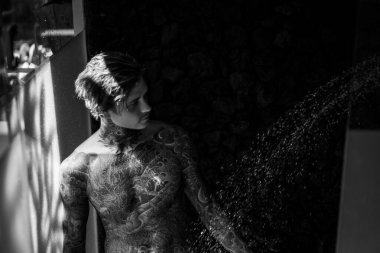 Duşta dövmeli yakışıklı bir genç. yaşam tarzı konsepti. 