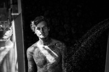 Duşta dövmeli yakışıklı bir genç. yaşam tarzı konsepti. 